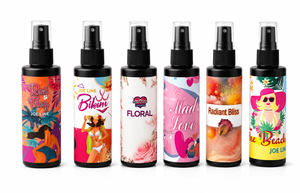Set of six fragrance body spray bottles with black sprayers, colorful label designs